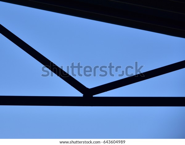 Black and blue abstract. Black straight lines\
of a roof against blue sky\
background.