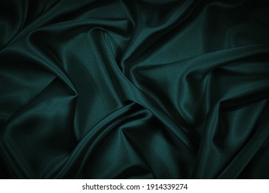  Black blue green abstract background. Dark green silk satin texture background. Beautiful wavy soft folds on the surface of the fabric. Teal elegant background with copy space for design. Web banner.