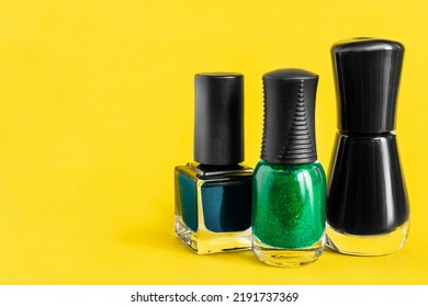 Black, Blue And Green Shimmer Nail Polish Jars On Yellow Background