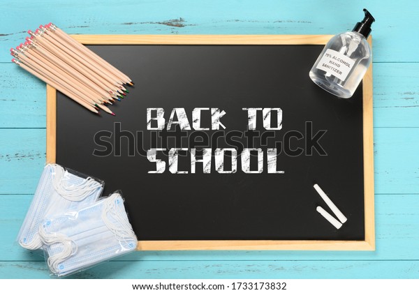 black board with back to school and safety mask and instant hand sanitizer and color pencils