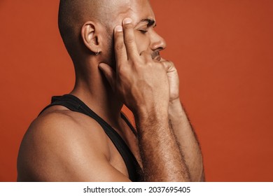 Black Bold Man With Headache Rubbing His Temples Isolated Over Brown Background