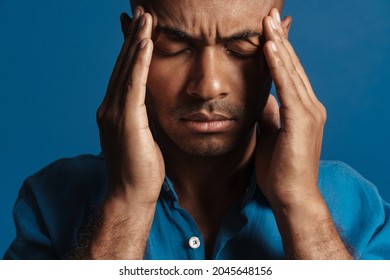 Black Bold Man With Headache Rubbing His Temples Isolated Over Blue Background