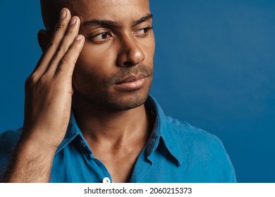 Black Bold Man With Headache Rubbing His Temple Isolated Over Blue Background