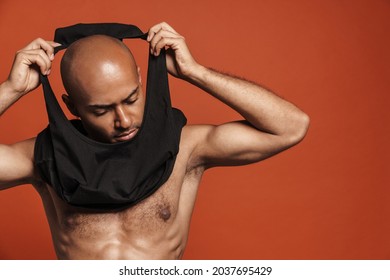 Black Bold Man Posing While Wearing Black Shirt Isolated Over Brown Background