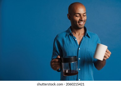 Black Bold Man Wearing Shirt Smiling While Drinking Coffee Isolated Over Blue Background