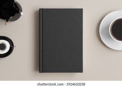 Black Book Mockup With A Coffee And Workspace Accessories On A Beige Table.