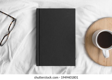 Black Book Mockup With A Cup Of Coffee And A Glasses On The Bed.