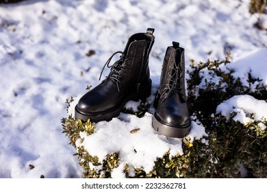 Black boots on snowy grass. Winter black leather women's shoes. Collection of warm shoes for women - Powered by Shutterstock