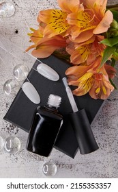 A Black Bottle Of White Lacquer Lies Open With A Brush On A Black Surface Along With Types And Colors