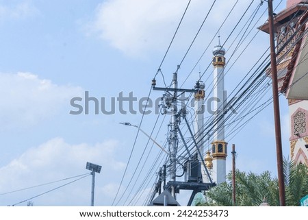 Black box silhouette and cable reel. Internet box or splitter box with fiber optic cables for high speed Internet communication wrapped on metal electric poles on a blue sky background. Selective focu