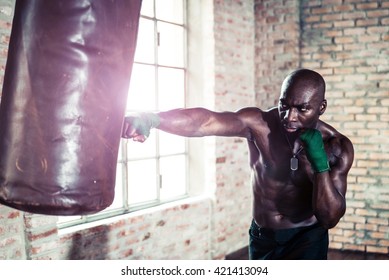 Black Boxer Punching The Heavy Bag In The Gym