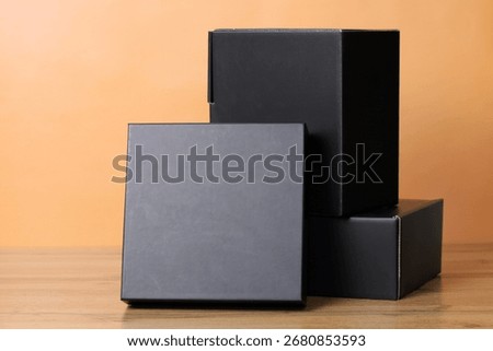 Black boxes stack on a wooden table, offering minimalist product packaging or gift presentation. Black Friday concept