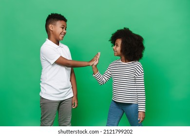 Black Boy And Girl Laughing While Giving High Fives Isolated Over Green Background