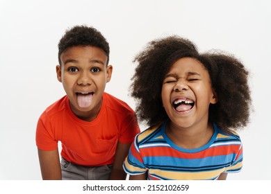 Black Boy And Girl Showing Their Tongues Together At Camera Isolated Over White Background