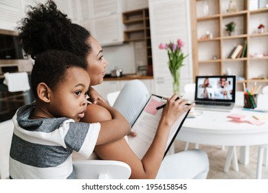 Black Boy Hugging His Mother While She Working With Laptop At Home