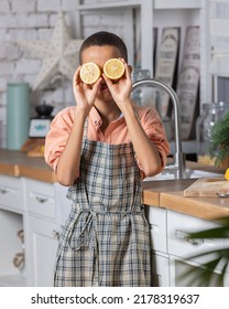 Black Boy Kid Cooking Fresh Lemon On Kitchen At Home. African Child Shows Tangerine Eyes