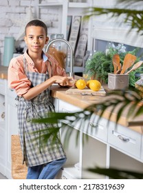 Black Boy Kid Cooking Fresh Lemon On Kitchen At Home. African Child Preparing On Table.