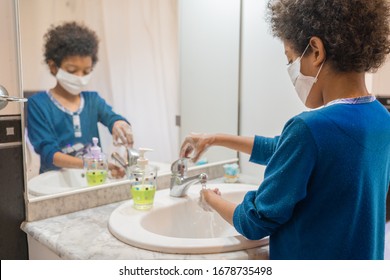 Black Boy With Medical Mask Washing His Hands With Soap In The Bathroom At Home To Avoid Infections Corona Virus