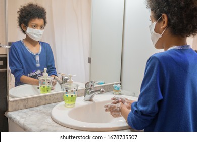 Black Boy With Medical Mask Washing His Hands With Soap In The Bathroom At Home To Avoid Infections Corona Virus