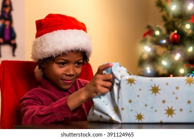 Black Boy Opening Christmas Present. Kid Opens Present On Christmas. I Wonder What's Inside. Finally I Can Open It.