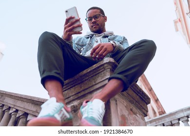 Black Boy Sitting On Ladder Using Mobile Phone