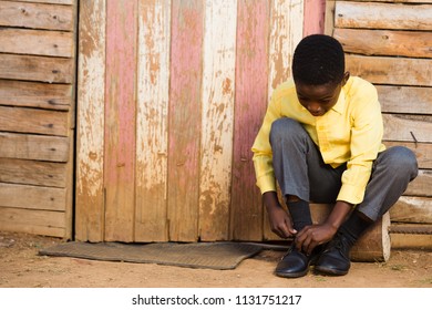 Black Boy Tieing His School Shoes While Sitting Down.