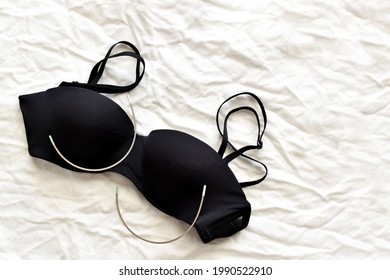 Black bra and stainless steel bra wire on fabric background. Photo can be used for Pros and Cons of Underwired Bras concept. Copy space is on the right side.