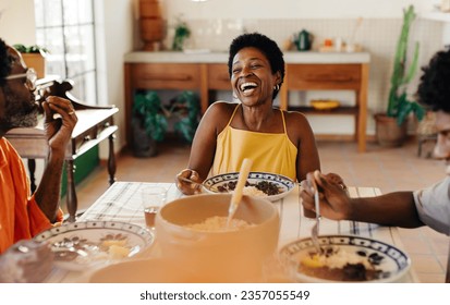 Black Brazilian family enjoys a traditional meal together at home. Laughter fills the air as they savor delicious Brazilian cuisine. Clay pots add a touch of authenticity to their dining table. - Powered by Shutterstock