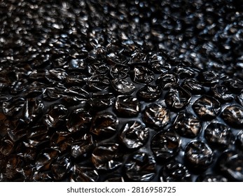 Black bubble wrap for packing, shipping, or security packaging to cushion breakable or valuable items during transport. The material has a dense pattern of air-filled bubbles for protection