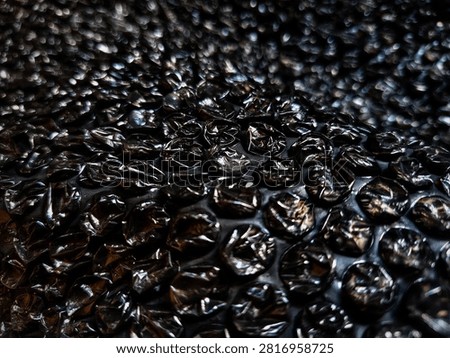 Black bubble wrap for packing, shipping, or security packaging to cushion breakable or valuable items during transport. The material has a dense pattern of air-filled bubbles for protection