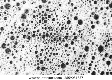 Black bubbles foam texture. Abstract pattern of soap suds. Macro closeup on white background. Cleaning product residue. Hygienic detergent surface. Artistic bubbly effect. Textured liquid structure.