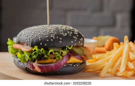 Black burger on a wooden background with potatoes and sauce - Shutterstock ID 1032258220
