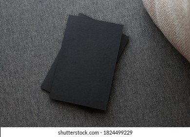 Black Business Card Mock Up With Golden Foil Logo On Black And Gray Cotton Sofa With Cream Pillow. Soft Focus Photo.