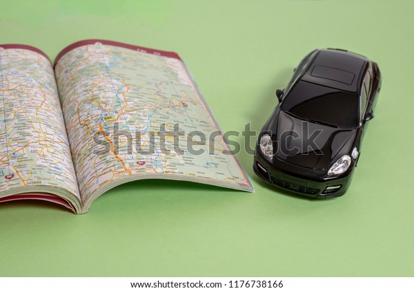Black business class toy car and road map in\
book version on green\
background