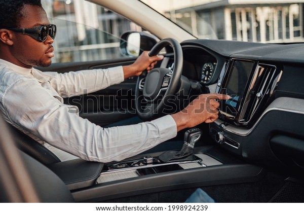 Black business man\
pressing on panel of car