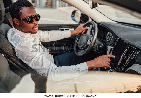 Black business man\
pressing on panel of car