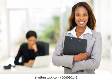 Black Business Woman Holding Clipboard With Colleague On Background