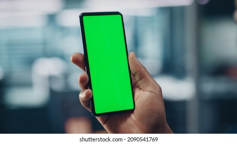 Black Businessman with Green Screen Chroma Key Smartphone in Office. African-American Businessperson using Internet, Social Media, Online Shopping with Mobile Phone Device. Over Shoulder - Powered by Shutterstock