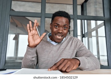 Black Businessman, Remote Teacher Wearing Headset Waving Hand Talking To Camera Conference Video Calling, Giving Webinar, Online Class, Distance Tutoring Working At Home Office, Web Cam View. Headshot