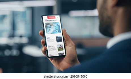 Black Businessman Using Smartphone for Checking Latest News in Office. African-American Businessperson Surfing the Internet over Mobile Phone Device. Over Shoulder Shot - Shutterstock ID 2090545090