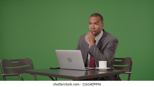 A Black Businessman Works On His Laptop Sitting At Cafe On Green Screen