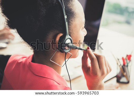 Black businesswoman as a telemarketing customer service agent wearing microphone headset working in the office - call center job concept, back view