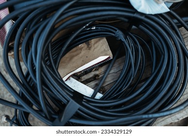A black cable coils in the recycling center with other objects in the background