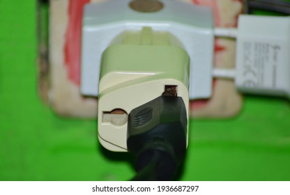 black cable head and socket with adapter plugged into the green wall socket