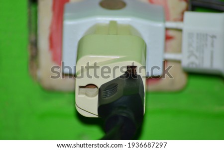 black cable head and socket with adapter plugged into the green wall socket