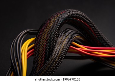 Black Cable with snake skin. Black braided wires in bundle on black background. Braided Sleeving. Data line protection. Wire Flame-retardant nylon tube