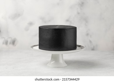 Black Cake On A Cake Stand, White Table.