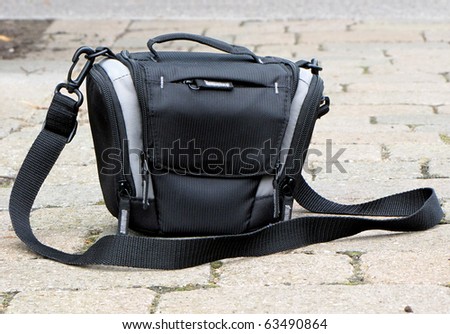 Black camera bag on cobblestone pavement. Foto d'archivio © 