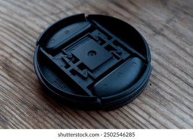 Black camera lens cap on a wooden surface - Powered by Shutterstock