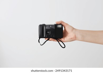 A black camera with a strap is being held by a person